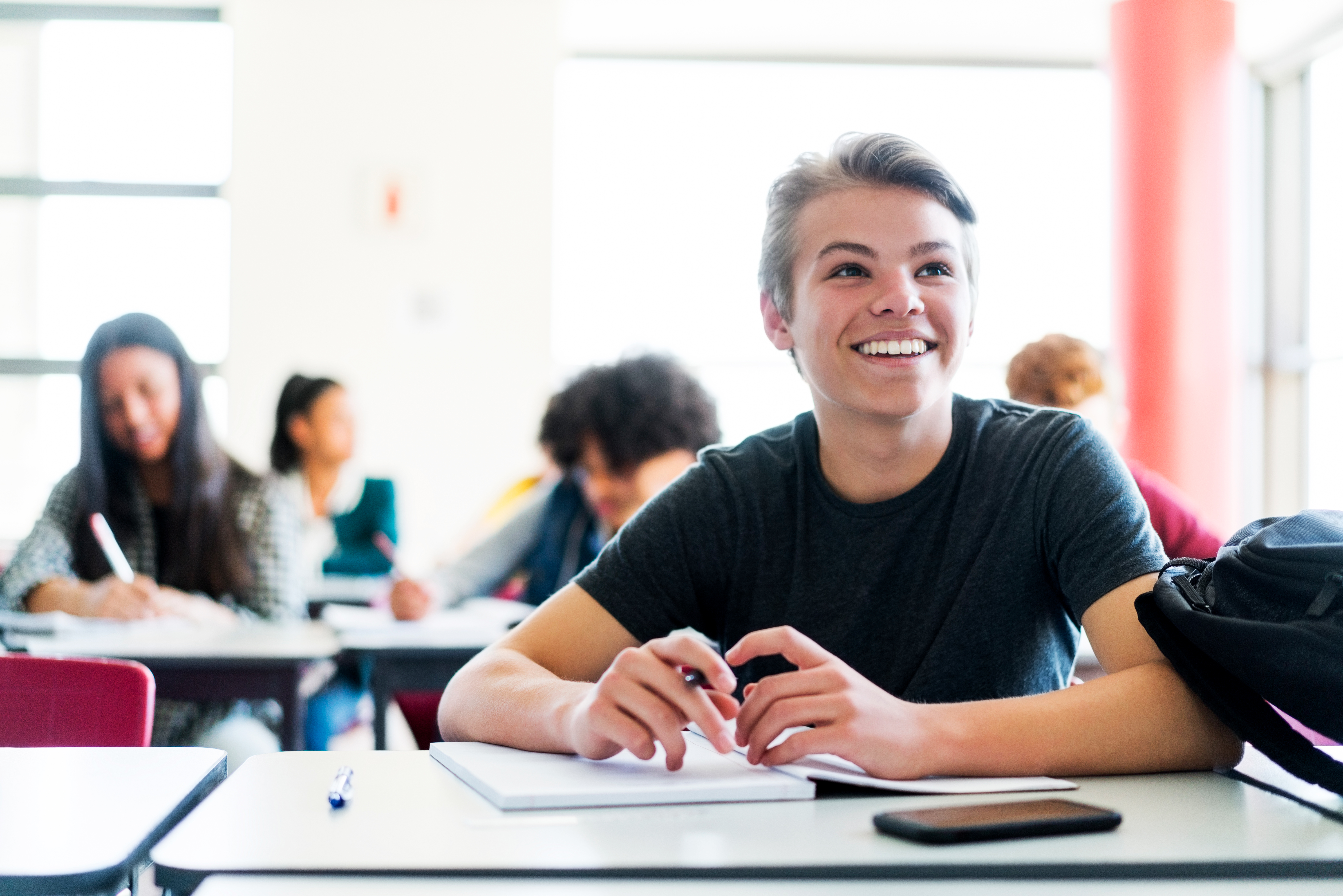 Smiling teenage boy sitting against friends - edited