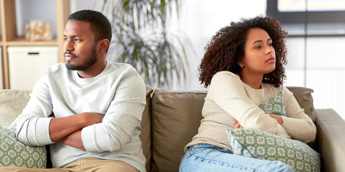 Young couple sitting away from each other as they encounter money issues in their marriage
