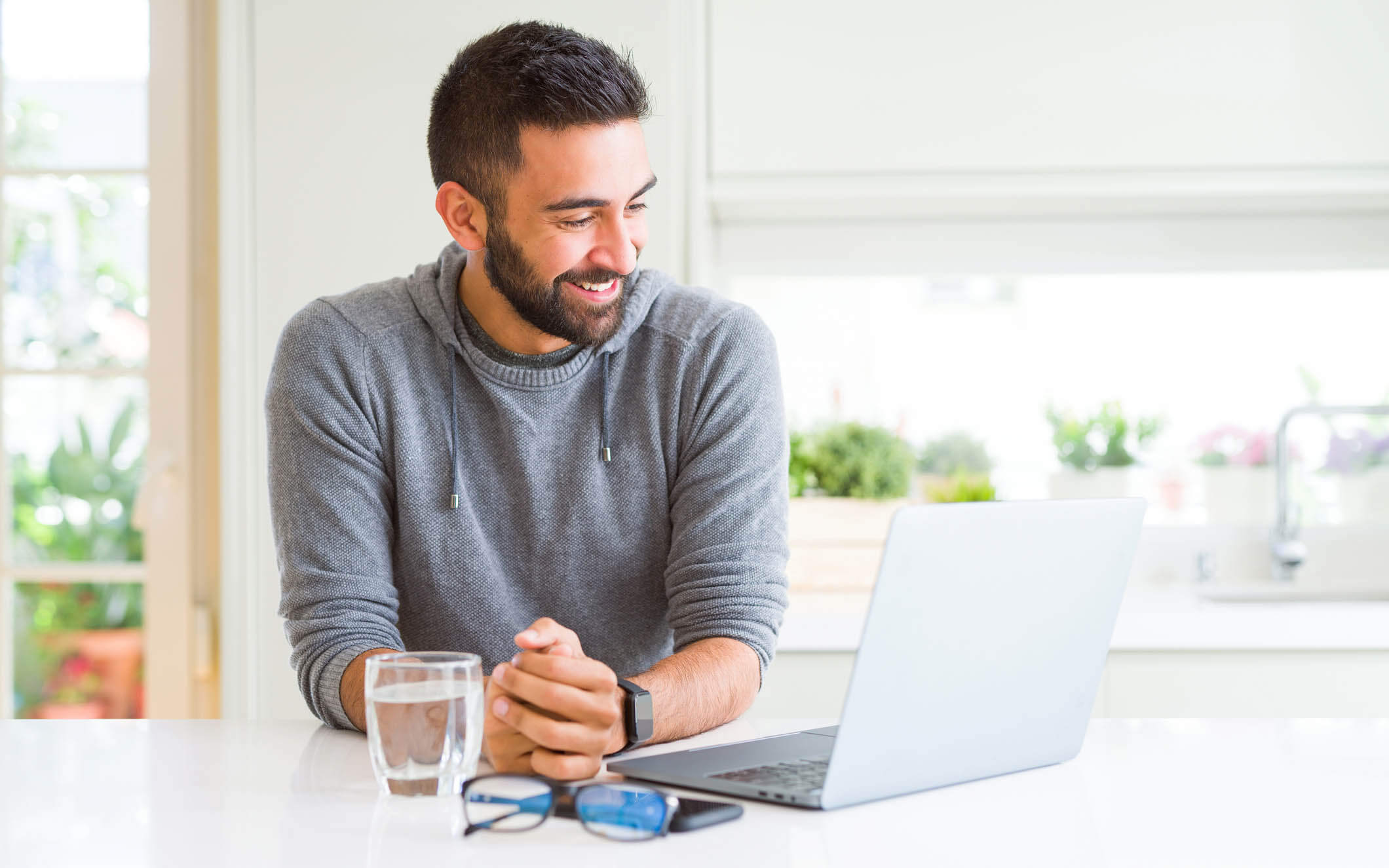 Man sitting at kitchen counter with laptop learning how to achieve financial goals.