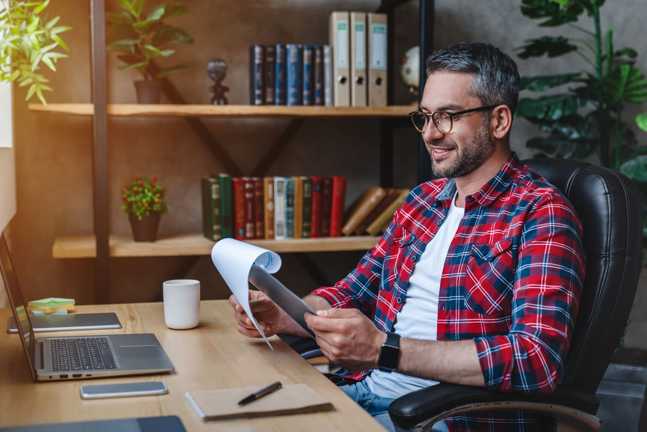 Middle-aged man in flannel shirt reviewing financing options for businesses at his desk