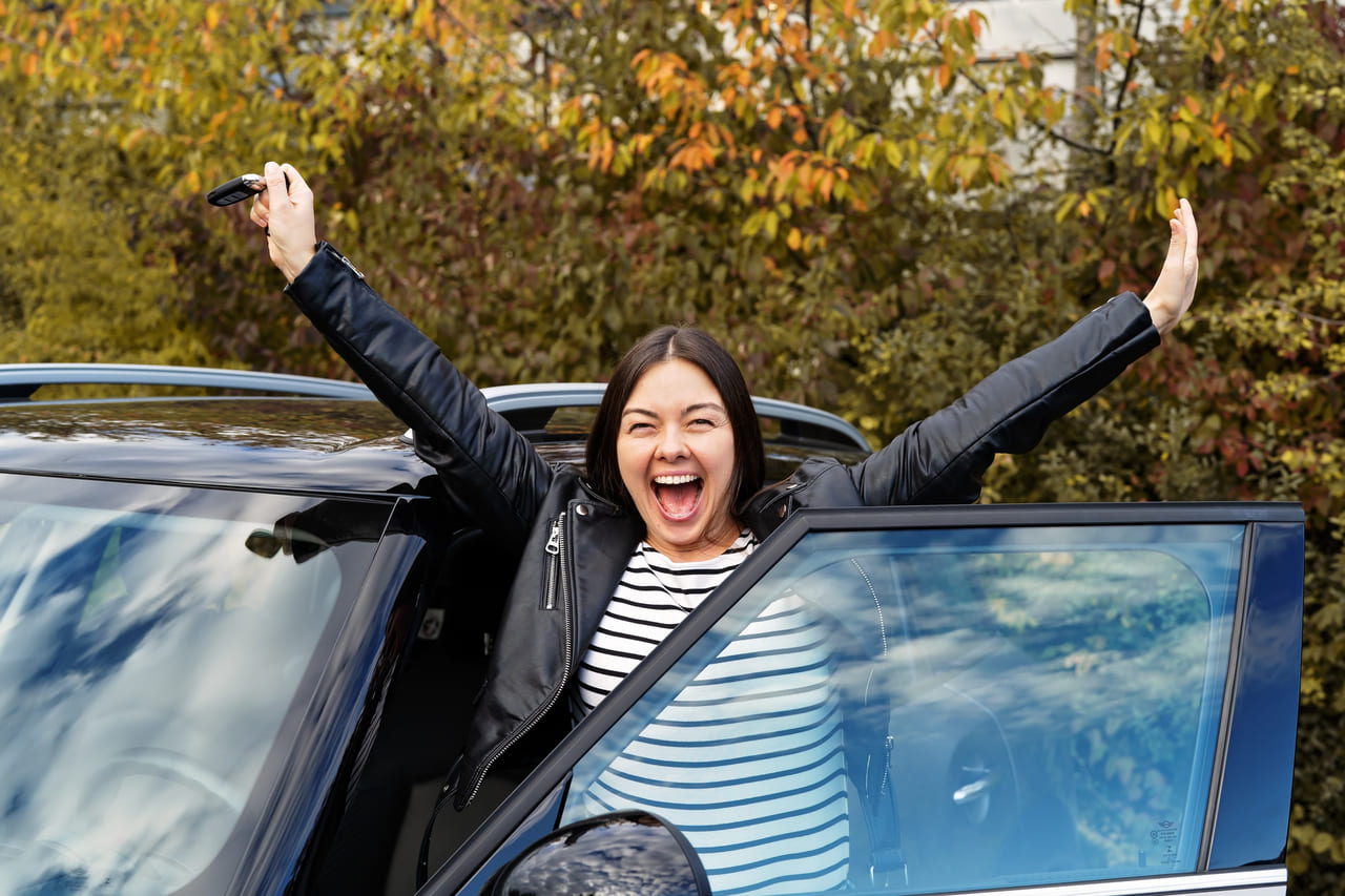 Happy woman in front of new car after using an auto loan