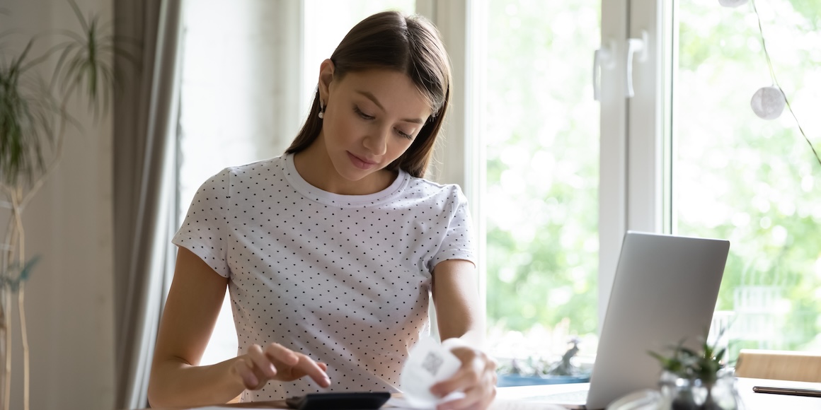 Young woman seated at a desk, learning how to cut her monthly expenses.