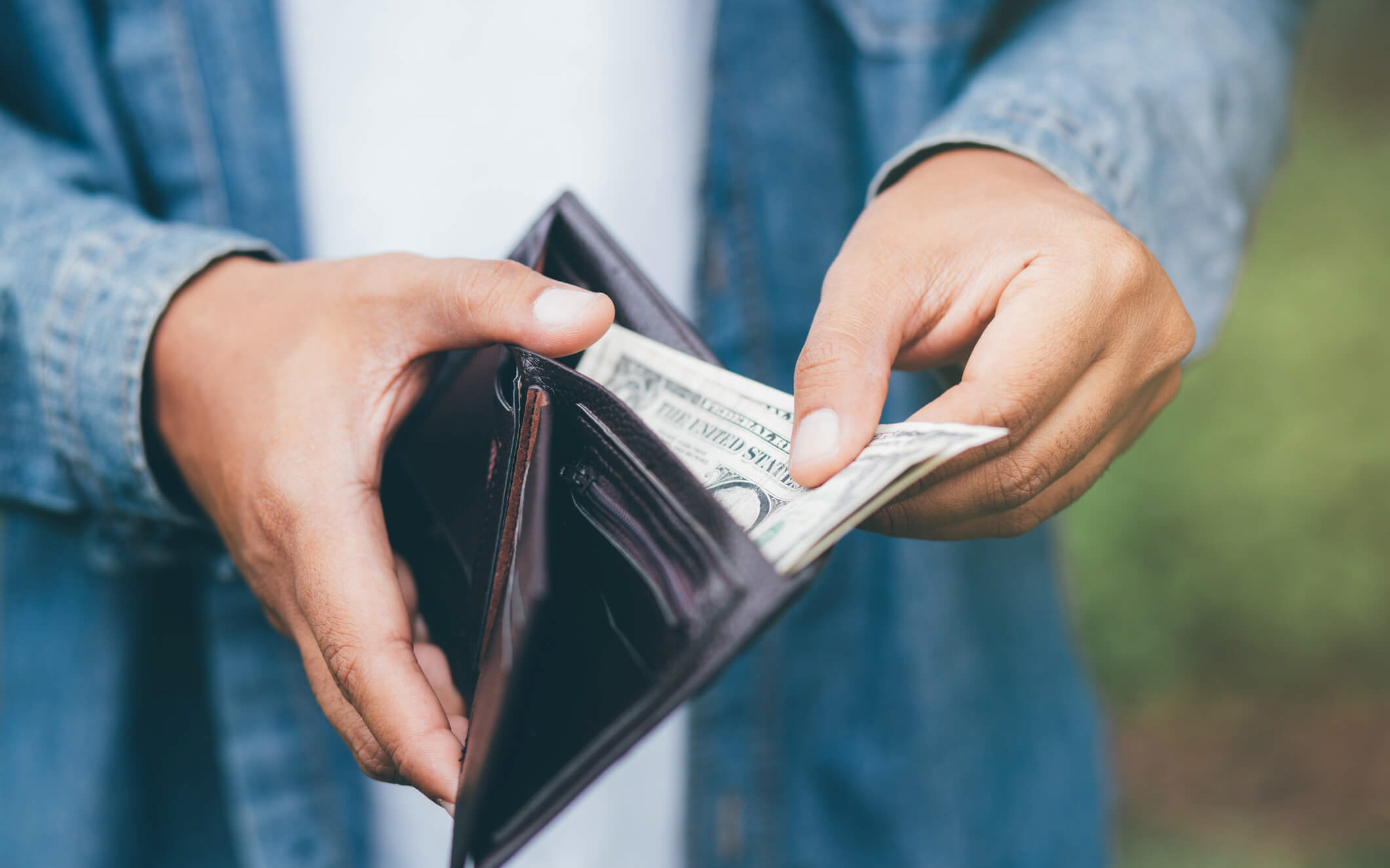Person holding a wallet and pulling out money.