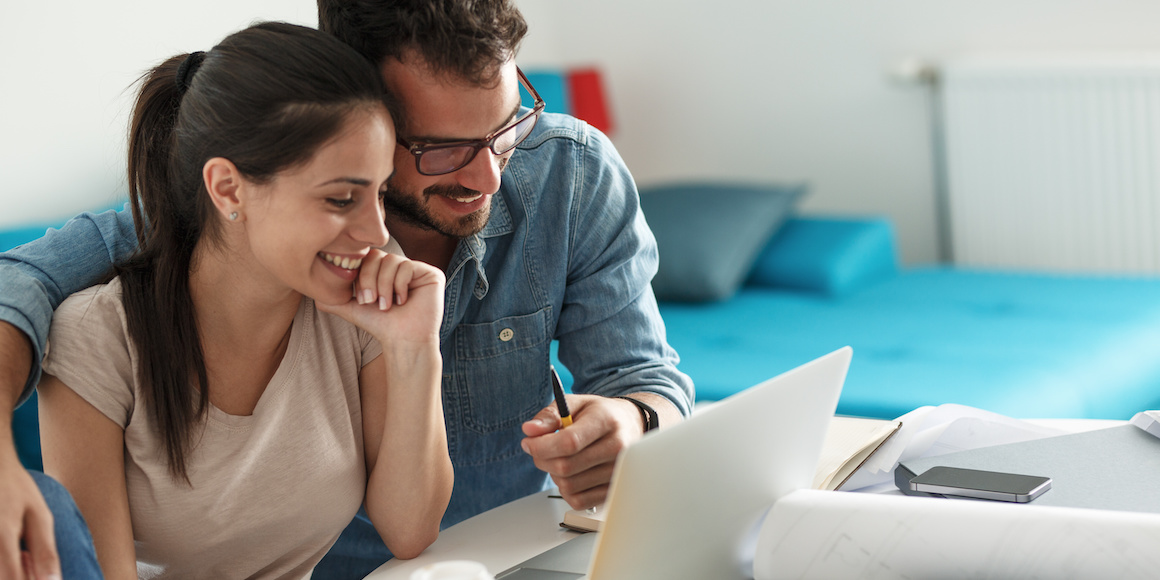 Happy couple examining their bank accounts, deciding when should couples merge their finances