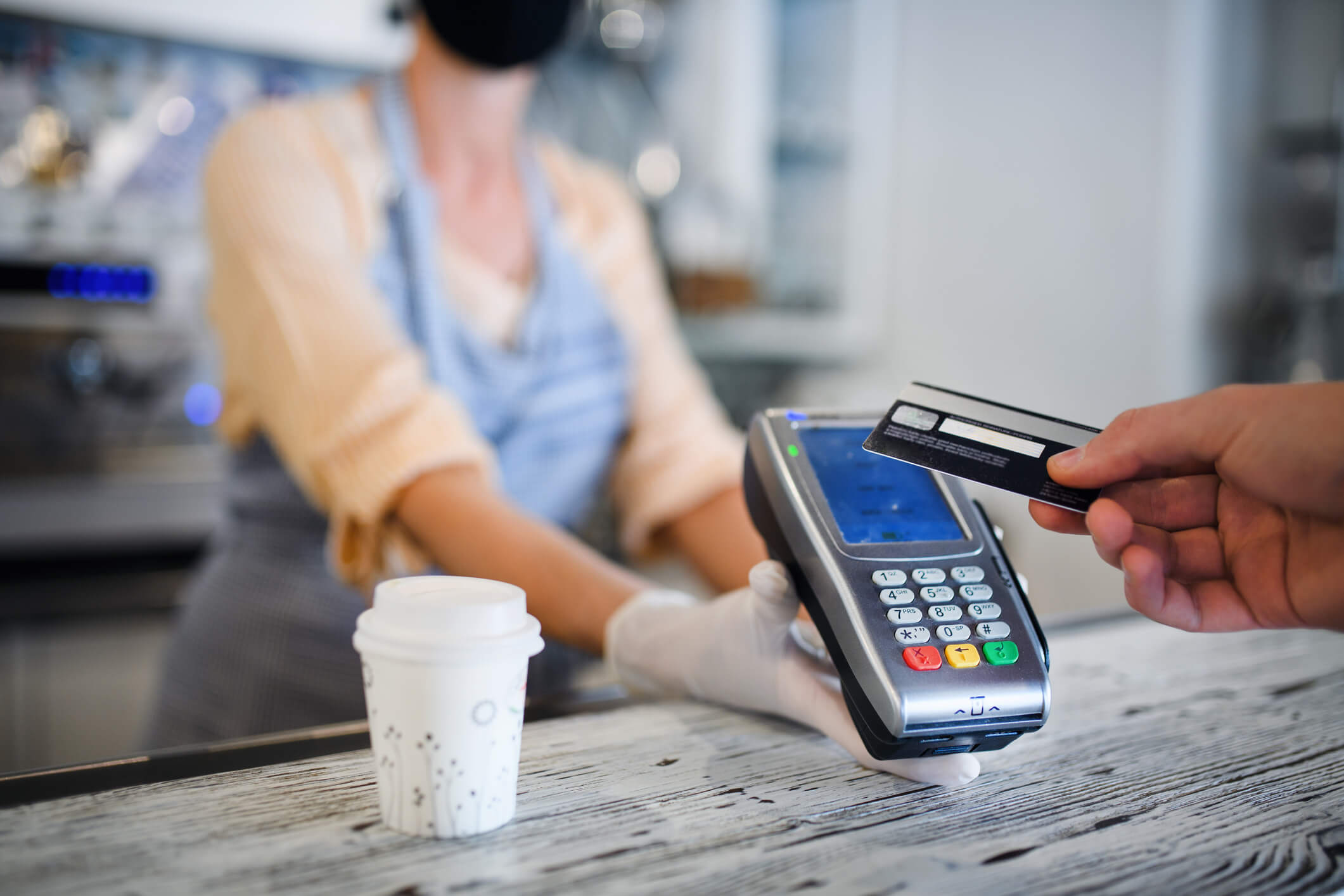 Customer using his card to make a contactless payment at a coffee shop.