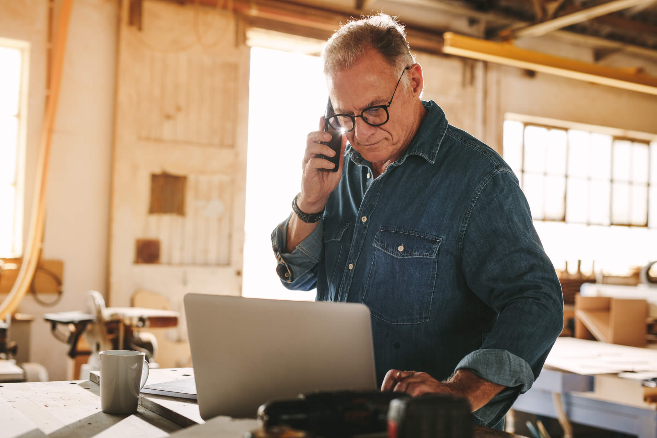Business owner checking his laptop while on the phone as he implements business tax planning strategies.
