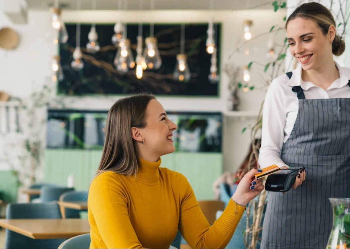 Woman making a purchase at a cafe with her card because she knows how debit cards work